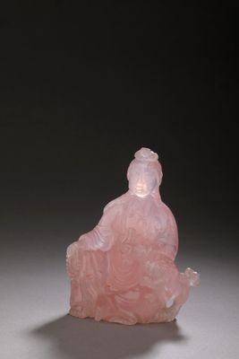 a pink jade figurine of a woman sitting on a rock