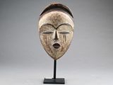 a wooden mask on a stand with a gray background