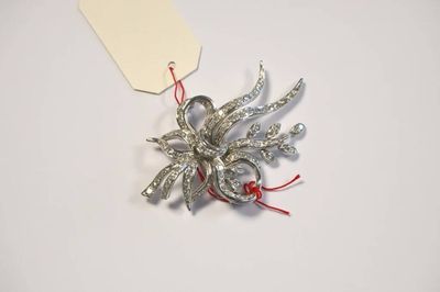 une broche en argent à laquelle est attaché un cordon rouge
