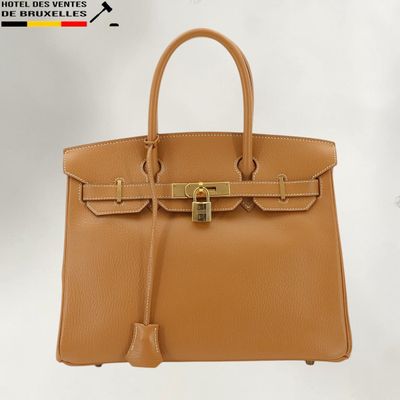 un sac à main en cuir marron muni d'un fermoir doré sur la poignée