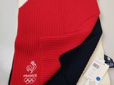 deux paires d'écharpes tricotées rouges, blanches et bleues posées sur une table