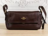 un sac à main marron de la marque Coach posé sur une table en bois