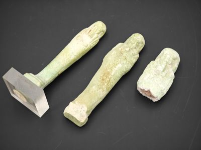 un gros plan sur trois outils en pierre posés sur une surface noire