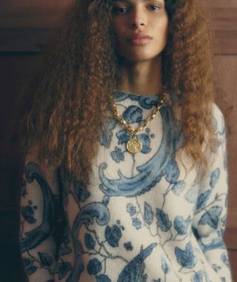 a woman with long curly hair wearing a blue and white sweater