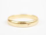 gros plan d'une bague en or sur une surface blanche