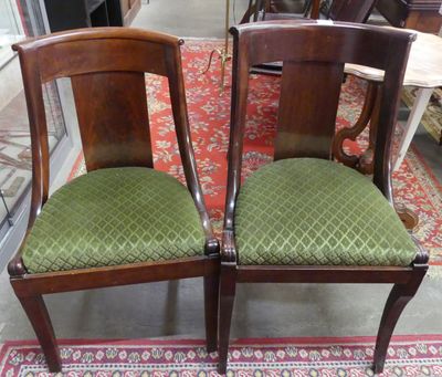 deux chaises en bois avec des coussins rembourrés verts, posées sur un tapis