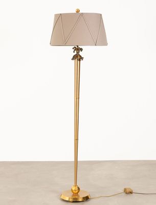 un lampadaire doré surmonté d'un abat-jour blanc