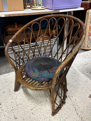 une chaise en osier avec un coussin posé dessus, dans une pièce