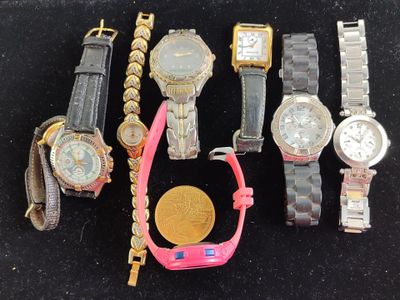 many watches and a gold coin on a black surface