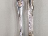 two silver spoons sitting on top of a table next to each other