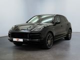 Une Porsche Cayenne noire est garée dans une pièce blanche