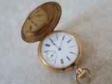 a gold pocket watch sitting on a white surface