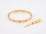 a close up of a gold bracelet and a pen on a white surface