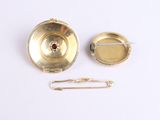 a small gold object with a pin on it