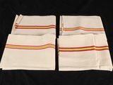 four white napkins with multi colored stripes on them on a black background