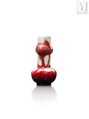 une photo d'un vase rouge et blanc posé sur une surface blanche