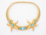 a gold necklace with turquoise stones and pearls on a white background