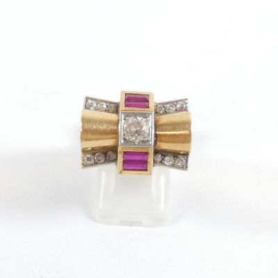 une photo d'une bague sertie d'un diamant et d'un rubis posée sur une surface claire