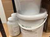 a bucket of liquid and a container of liquid on a shelf