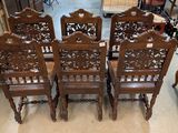 six wooden chairs with carved back and arms in a room