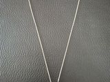 a necklace with a four leaf clover on it sitting on a black surface