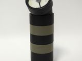 une horloge en noir et blanc posée sur un cylindre noir