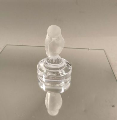 une figurine en verre représentant un oiseau perché sur une table en verre