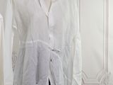 a white shirt on a mannequin stand in front of a white wall