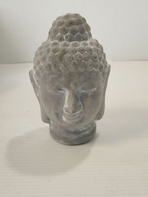 une petite statue représentant une tête de Bouddha, posée sur une table