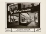 an old black and white photo of a storefront with people walking by