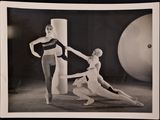 black and white photograph of two women in a dance pose with a giant ball in the background