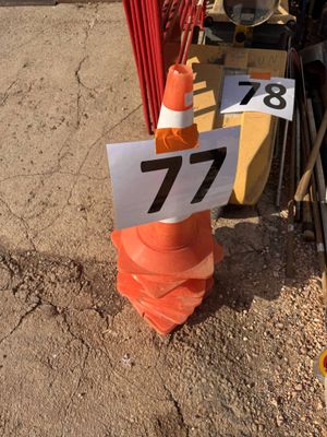 un cône de signalisation surmonté d'un panneau, à côté d'un tas de matériel de chantier