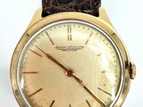 a close up of a gold watch with a brown leather strap