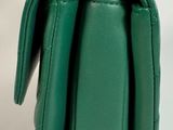 the green purse has a gold clasp on the front