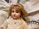 a doll that is sitting on a bed with a white sheet