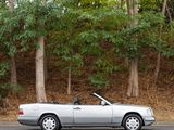 a silver car driving down the road in front of trees