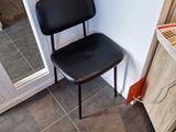 a black chair sitting in front of a white wall