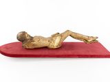 statue of a man laying on a red cushion