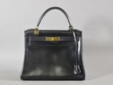 un sac à main en cuir noir avec des finitions dorées sur fond blanc