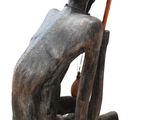statue représentant un homme assis sur une chaise, un bâton à la main