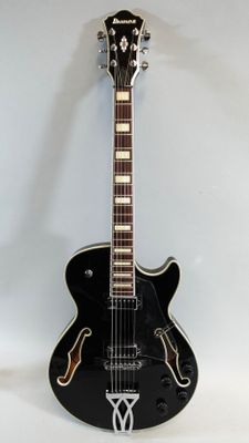 an image of a black electric guitar sitting on top of a white surface