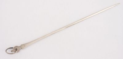 une vieille cuillère en argent avec un manche en métal posée sur une surface blanche