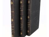 three black books with gold bindings on them sitting next to each other