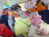 a pile of clothes that is sitting on a bed