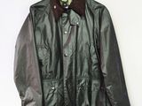 veste en cuir à col en fourrure, suspendue à un cintre contre un mur blanc