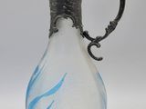 une image représentant un vase en verre muni d'une poignée en argent, sur fond blanc