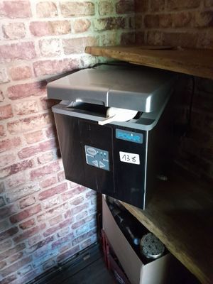 un petit réfrigérateur posé sur une étagère dans un coin de la pièce