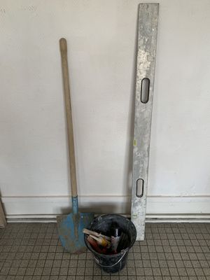 a bucket and a shovel on the floor next to a wall