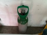 a green gas bottle sitting next to a yellow fire hydrant