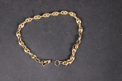 gros plan d'un bracelet en chaîne en or sur une surface noire